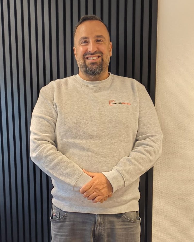 Dario Saponaro, Geschäftsführer der Fenstermacher24 GmbH, im Fenstermacher-Pullover vor einer schwarzen Akustikwand